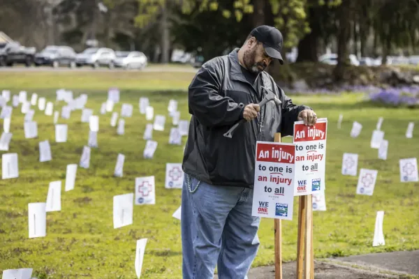 John Henson uses a hammer to install a sign at the Local 793 picnic which reads "An injury to one is an injury to all"