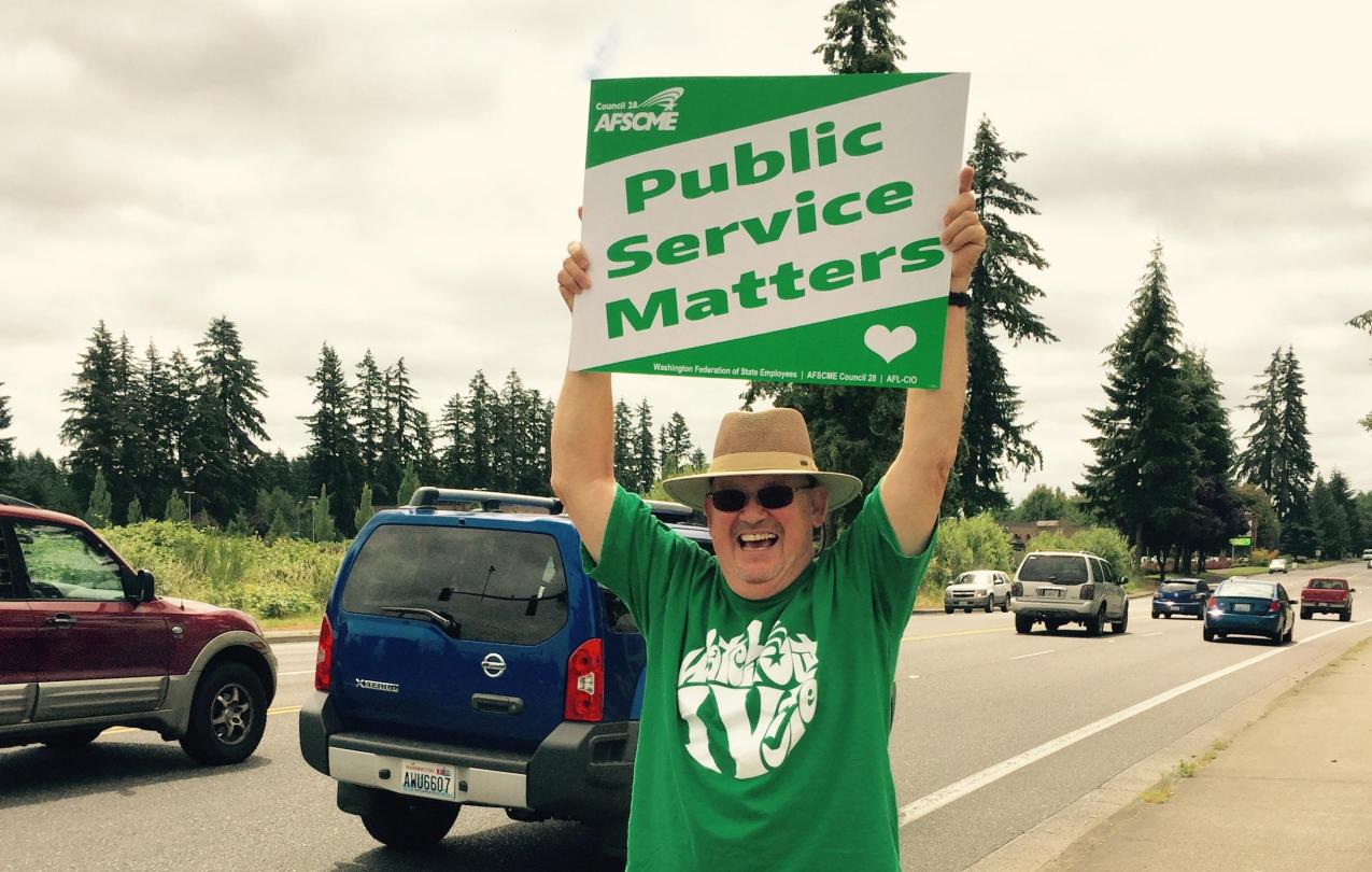 Tim Hughes holds up a sign saying "Public Service Matters"