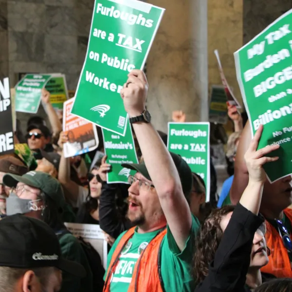 Members at the capitol holding No Furloughs signs